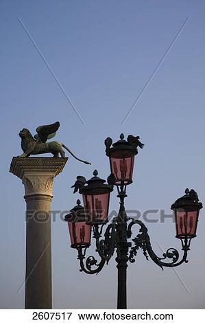 Stock Photo - Heraldic lion sculpture on column and lamp post against blue sky, Piazza San Marco, Veneto, Venice, Italy . Fotosearch
