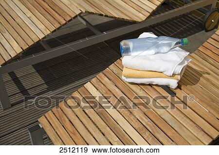 High angle view of bottle on towels on deck chair View Large Photo Image Stock Photo - High angle view of bottle on towels on deck chair . Fotosearch