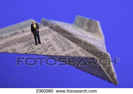 Stock Image - High angle view of figurine of businessman standing on paper airplane . Fotosearch