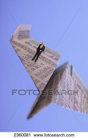 Stock Image - High angle view of figurine of businessman standing on paper airplane . Fotosearch