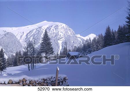 Stock Image - Log cabin on snow-covered landscape, Alps, Switzerland . Fotosearch
