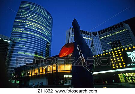Stock Image - Low angle view of office buildings lit up at dusk, La Defense, Paris, Ile-De-France, France . Fotosearch