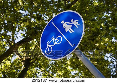 Stock Photo - Low angle view of pedestrian walkway signpost against tree . Fotosearch