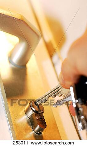 Stock Image - Low angle view of person's hand opening door with key . Fotosearch