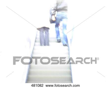Stock Image - Low angle view of two people on escalator . Fotosearch