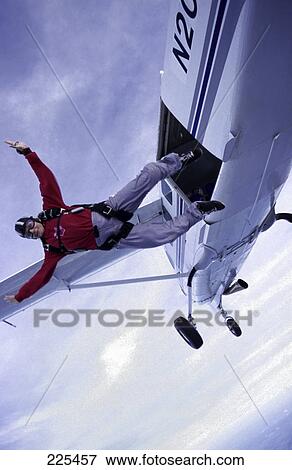 Stock Photo - Man jumping out of plane, low angle view . Fotosearch