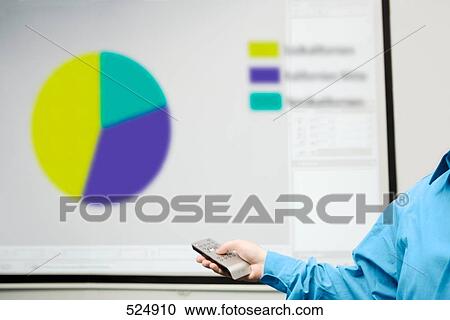 Stock Image - Man's hand holding remote with projection screen in background . Fotosearch