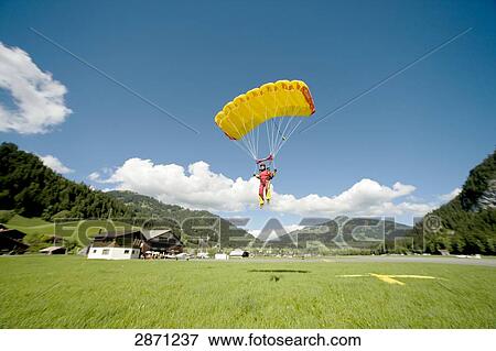 Stock Photo - parachute jumper landing, full shot . Fotosearch
