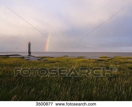 Stock Photo - Rainbow above the North Sea at Fedderwardersiel, Germany . Fotosearch