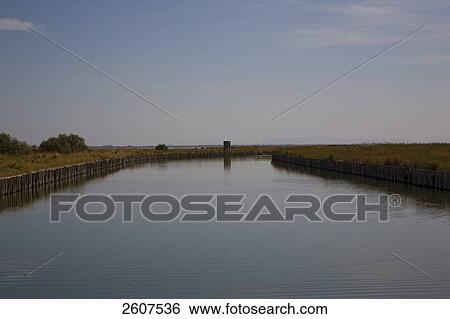 Stock Photograph - River flowing through field, Valli Di Comacchio, Emilia-Romagna, Italy . Fotosearch