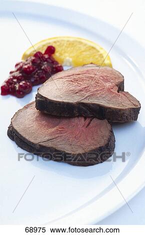 Stock Photography - Roasted steaks with slice of lemon and cranberry sauce on plate . Fotosearch