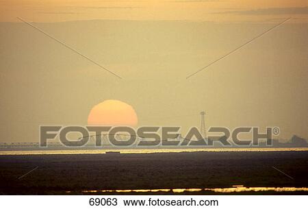 Stock Image - Silhouette of bridge against setting sun, Mecklenburg-Western Pomerania, Germany . Fotosearch