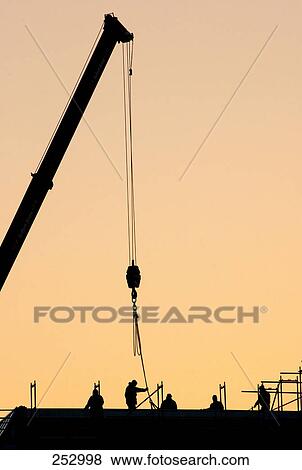 Stock Photo - Silhouette of workers and crane at construction site . Fotosearch