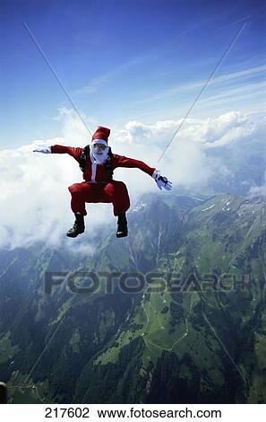 Stock Image - Skydiver in Santa Claus costume falling down towards ground . Fotosearch