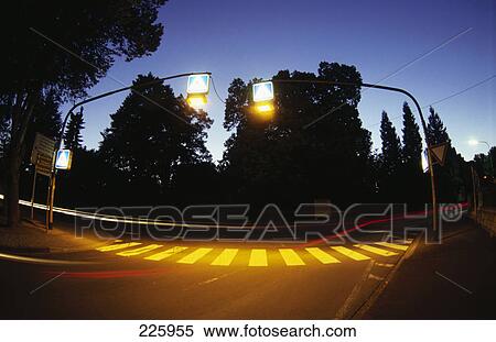 Stock Photography - Streetlight lit up above zebra crossing at dusk, Germany . Fotosearch