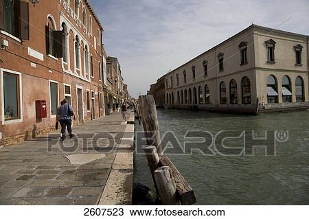 Stock Image - Tourists walking along canal, Rio del Vetrai, Isola Murano, Veneto, Venice, Italy . Fotosearch