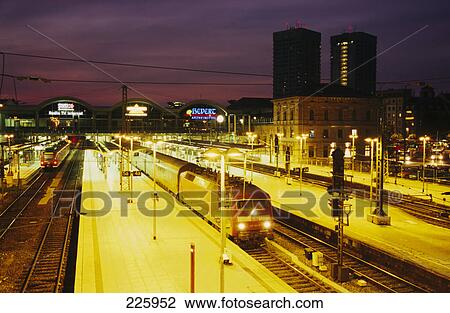 Stock Image - Trains at station lit up at dusk, Mainz, Germany . Fotosearch