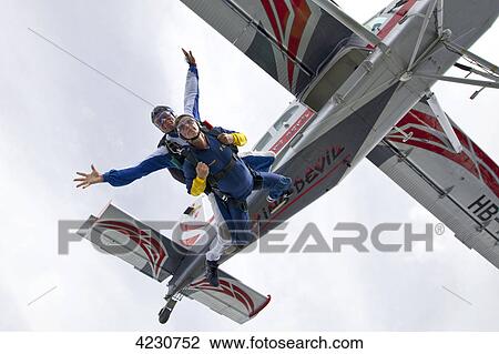 Stock Image - Two men doing parachute jumping, Saanen, Canton Bern, Switzerland . Fotosearch