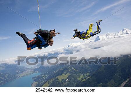 Stock Image - two people doing parachute jumping, full shot . Fotosearch