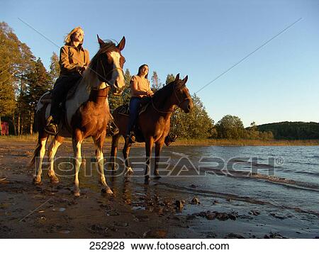 Two women sitting on horses at beach, Lake Ivag, Sweden View Large Photo Image Stock Photo - Two women sitting on horses at beach, Lake Ivag, Sweden . Fotosearch