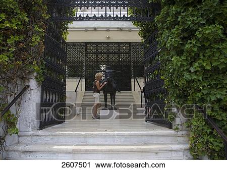 Stock Image - Woman standing near animal sculpture in front of museum, Veneto, Venice, Italy . Fotosearch