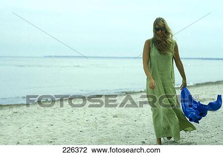 Stock Image - Woman walking on beach with sarong . Fotosearch
