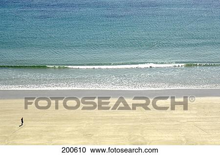 Stock Image - Aerial view of man walking on beach . Fotosearch