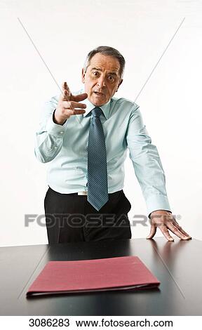 Stock Image - Angry businessman pointing his finger at the camera, front view . Fotosearch