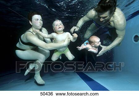 Stock Photograph - Babies swimming with parents in indoor pool, underwater view . Fotosearch