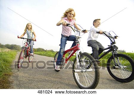Bother and sisters cycling through field View Large Photo Image Picture - Bother and sisters cycling through field . Fotosearch