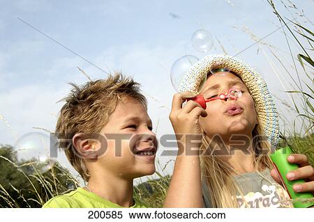 Boy and girl blowing bubbles View Large Photo Image Stock Photography - Boy and girl blowing bubbles . Fotosearch