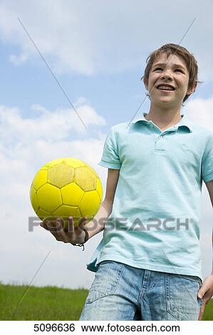 Boy holding football outdoors View Large Photo Image Stock Photograph - Boy holding football outdoors . Fotosearch