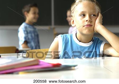 Boy looking sad in classroom View Large Photo Image Stock Photo - Boy looking sad in classroom . Fotosearch