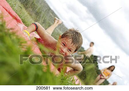 Stock Image - Boy lying on grass and smiling . Fotosearch