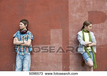 Stock Image - Boy with headphones and girl leaning at wall . Fotosearch