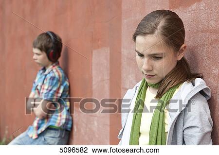 Stock Image - Boy with headphones and girl leaning at wall . Fotosearch