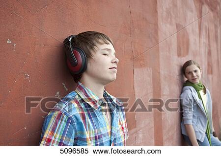 Boy with headphones and girl leaning at wall View Large Photo Image Stock Photography - Boy with headphones and girl leaning at wall . Fotosearch