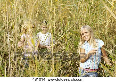 Brother and sisters playing in field View Large Photo Image Picture - Brother and sisters playing in field . Fotosearch