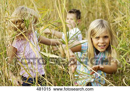 Brother and sisters playing in field View Large Photo Image Stock Photography - Brother and sisters playing in field . Fotosearch