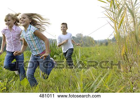 Stock Image - Brother and sisters running in field . Fotosearch
