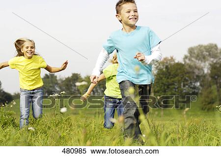 Stock Photography - Brother and sisters running in field . Fotosearch