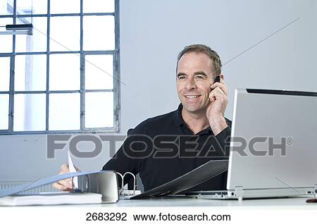 businessman and his notebook using his mobile phone, portrait View Large Photo Image Stock Image - businessman and his notebook using his mobile phone, portrait . Fotosearch
