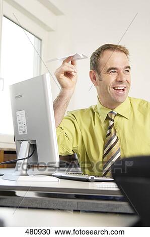 Stock Image - Businessman flying paper plane in office . Fotosearch