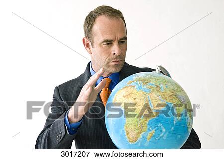 Stock Photo - Businessman looking at a globe . Fotosearch