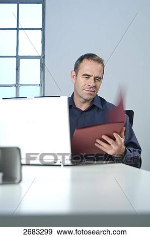 Businessman looking at file in office View Large Photo Image Stock Photo - Businessman looking at file in office . Fotosearch