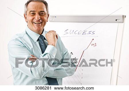 Stock Image - Businessman standing in front of a flip chart, facing camera . Fotosearch