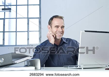 Businessman using laptop and smiling in office View Large Photo Image Picture - Businessman using laptop and smiling in office . Fotosearch