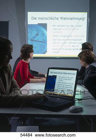 Businessman using laptop with his colleagues looking at projection screen in background View Large Photo Image Picture - Businessman using laptop with his colleagues looking at projection screen in background . Fotosearch