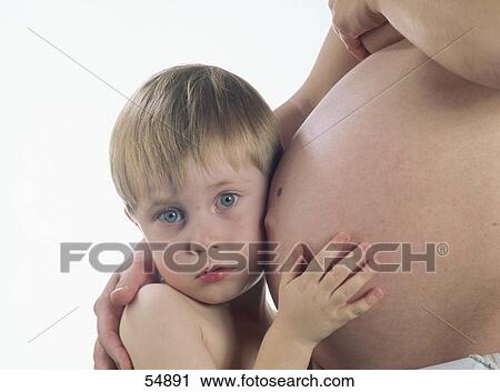 Stock Image - Child hearing at belly of pregnant mother . Fotosearch