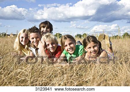 Children lying in field, facing camera View Large Photo Image Stock Image - Children lying in field, facing camera . Fotosearch